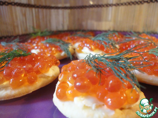 Canapés with red caviar on homemade cheese crackers