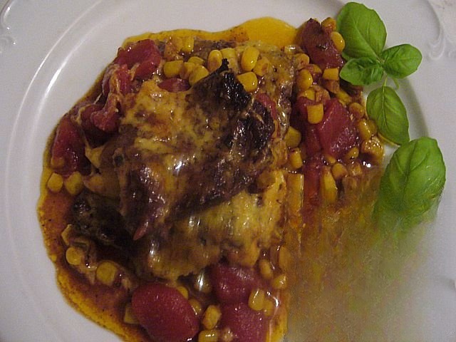 The meat in the oven with corn and tomatoes